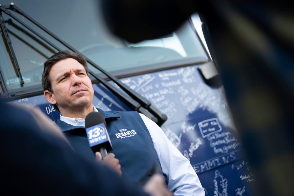 Ron DeSantis speaks to a reporter in front of his bus during a campaign event at The Drive-In.