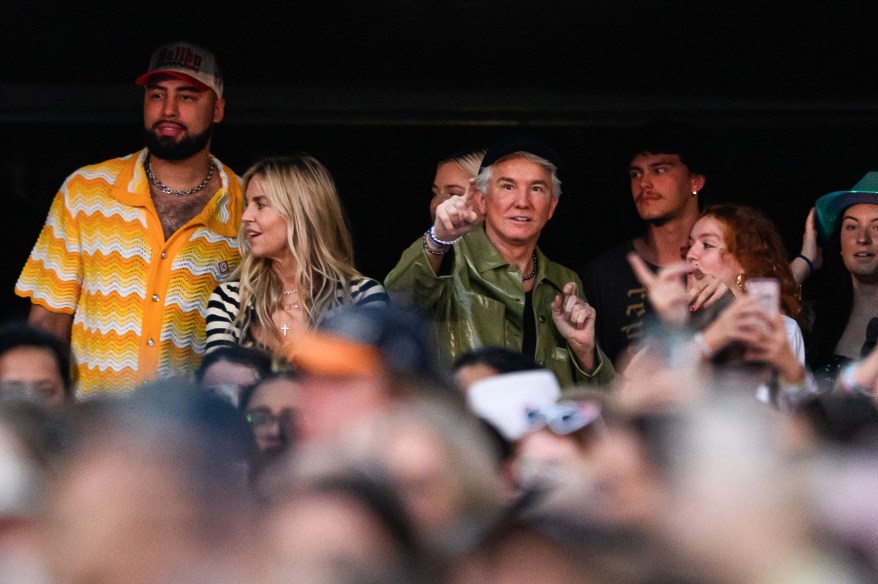 Travis Kelce, Baz Luhrmann, and Taylor Swift performing on stage in front of a large crowd at Accor Stadium in Sydney.