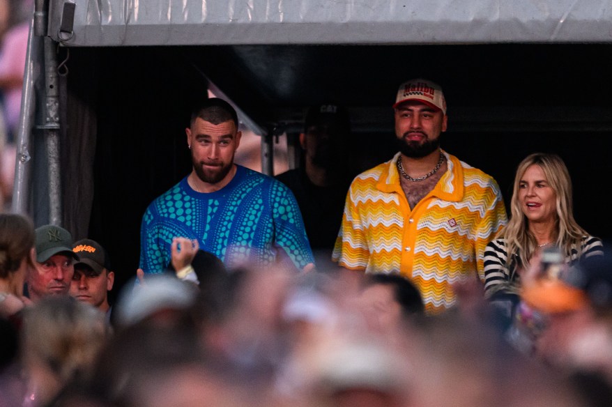 Travis Kelce standing beside other people in a doorway.