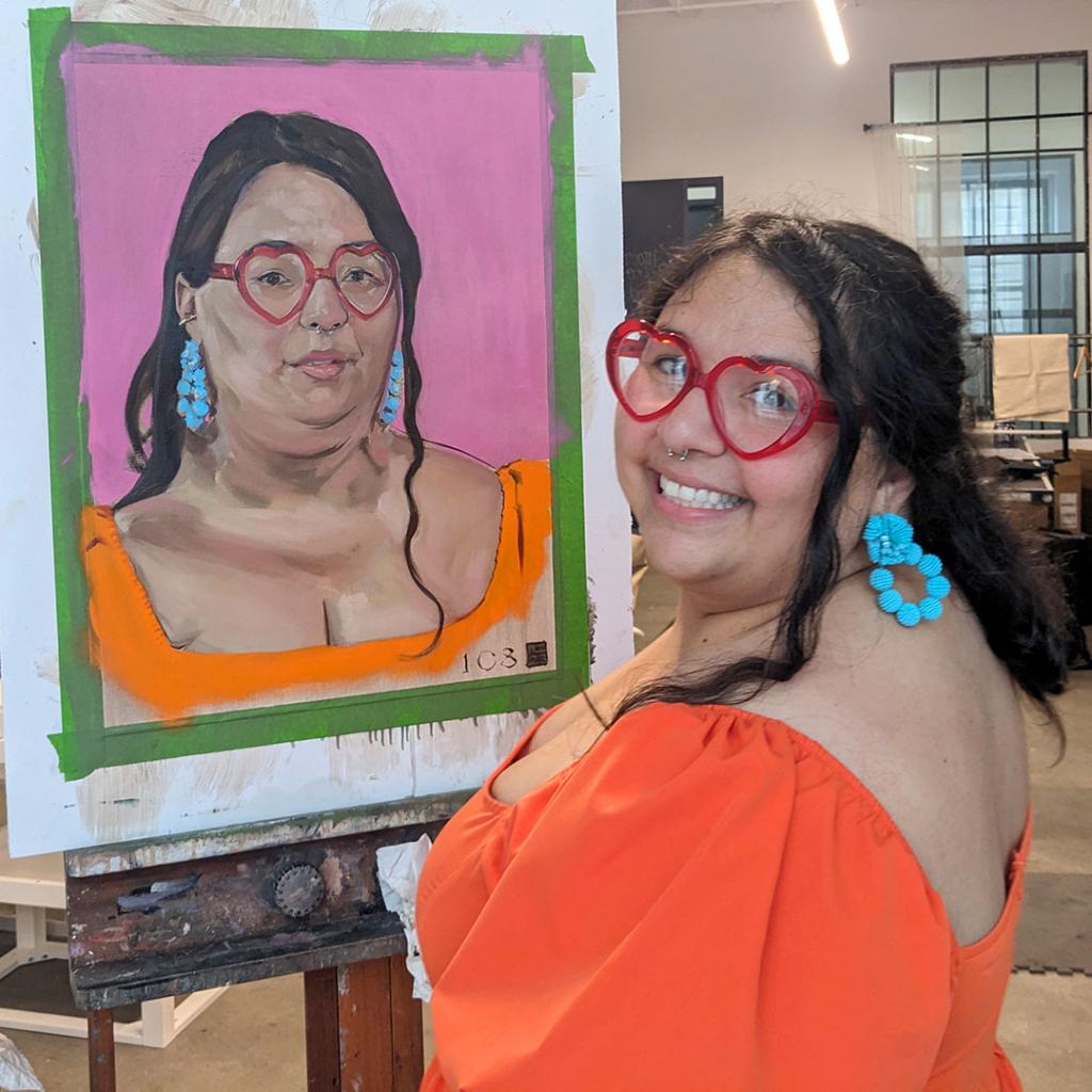 Samantha Figueroa beams as she stands next to her portrait. 