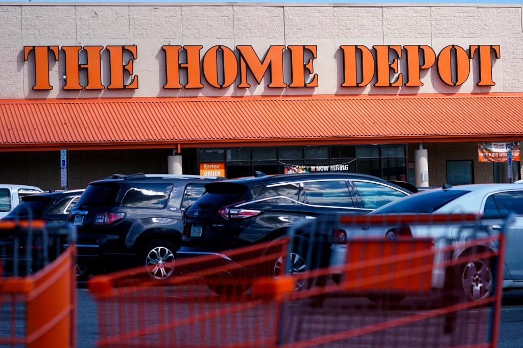 Shopping carts parked outside a Home Depot store in Philadelphia, with a sign indicating its planned acquisition of SRS Distribution.