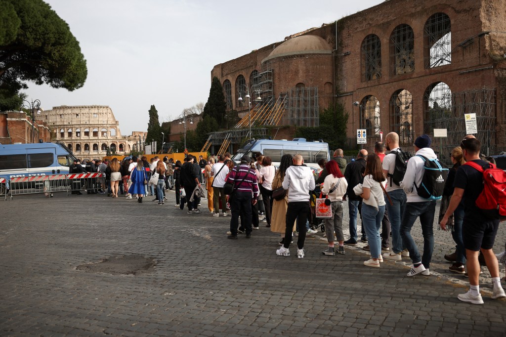 People wait in line as police officers do security check during Good Friday celebrations, near the Colosseum, in Rome, Italy on March 29, 2024.