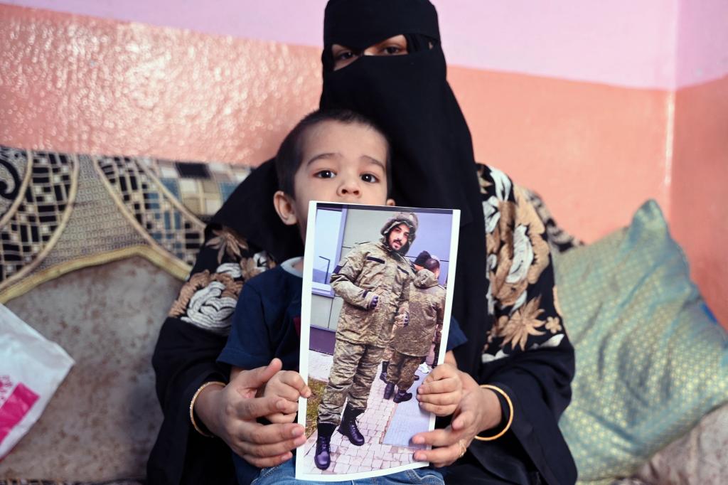 This photo taken on February 22, 2024 shows a picture printout of Indian national Mohammed Asfan, seen wearing Russian military fatigues who last called family from the southern Russian city of Rostov-on-Don before being deployed amid the conflict in Ukraine, being held by his wife Asma Shireen and their child in Hyderabad