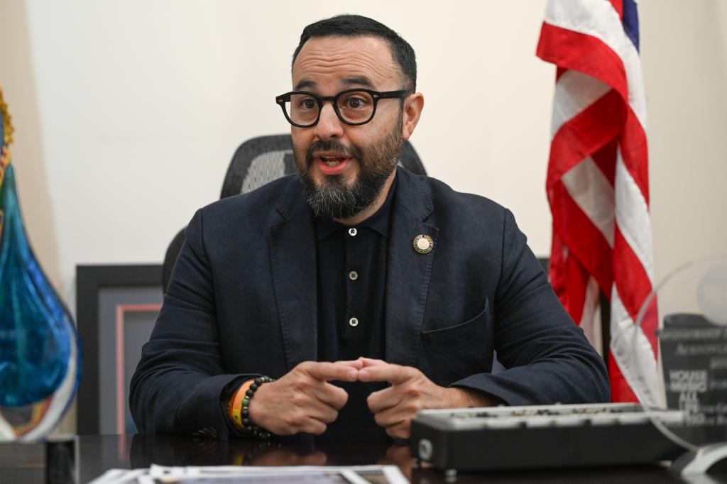 District 21 Council Member Francisco Moya sitting at a desk with a microphone in Crotona, Queens, NY