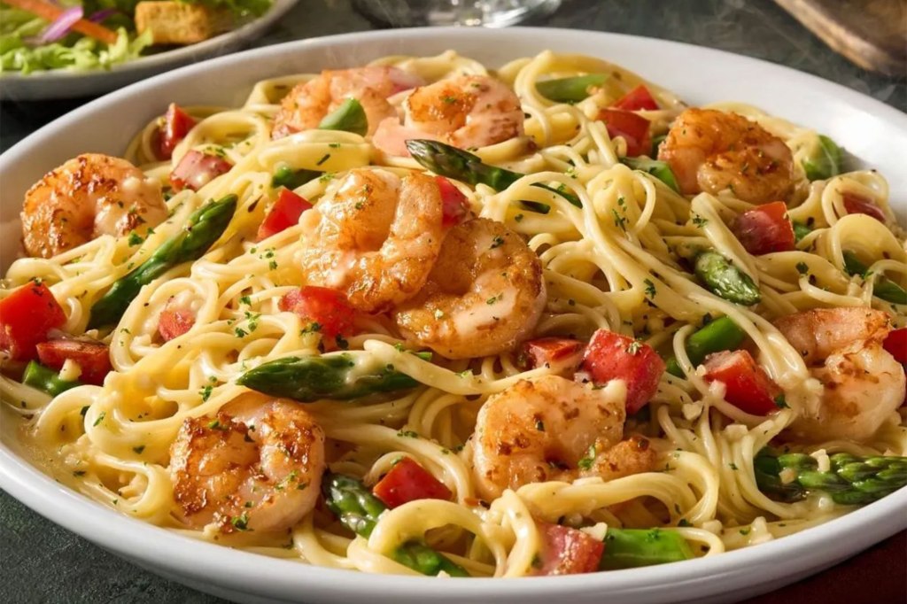 A plate of pasta with shrimp and asparagus at Olive Garden