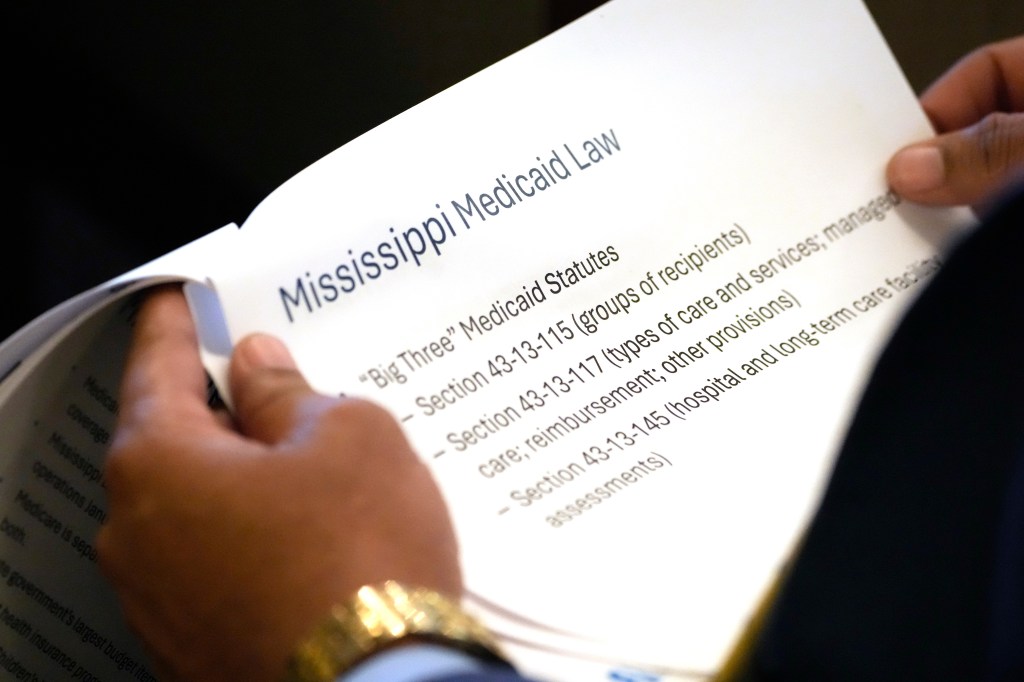 A person holding a document about Mississippi Medicaid provided to the House Medicaid Committee at the Mississippi Capitol.