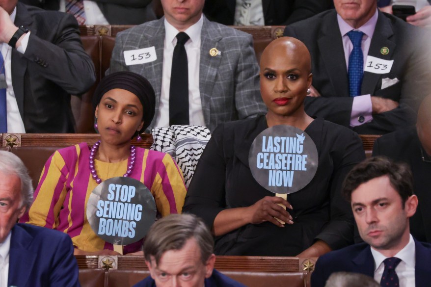 U.S. Rep. Ilhan Omar (D-MN) (L) and Rep. Ayanna Pressley (D-MA) hold up signs.