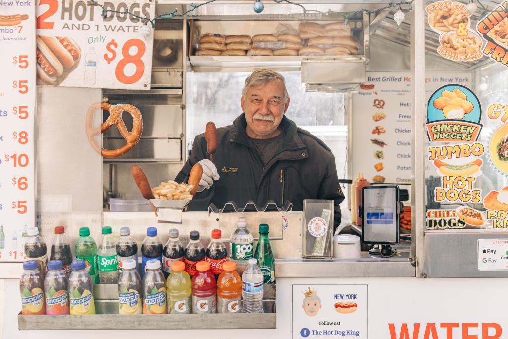 Dan Rossi holding a corndog inside his cart outside the Met. 