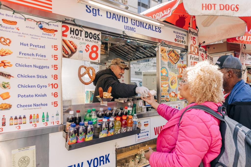 Rossi handing a hot dog to a customer.