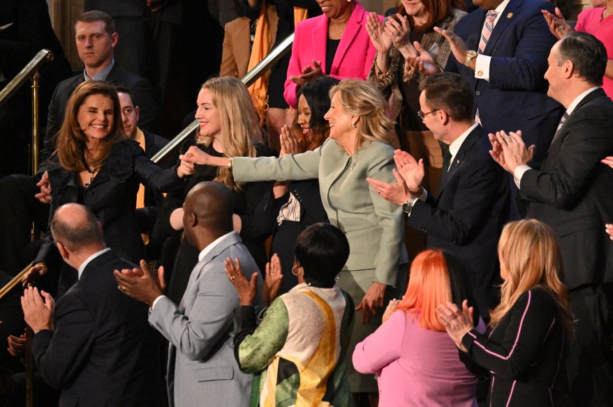 Maria Shriver (L), holds hands with US First Lady Jill Biden.