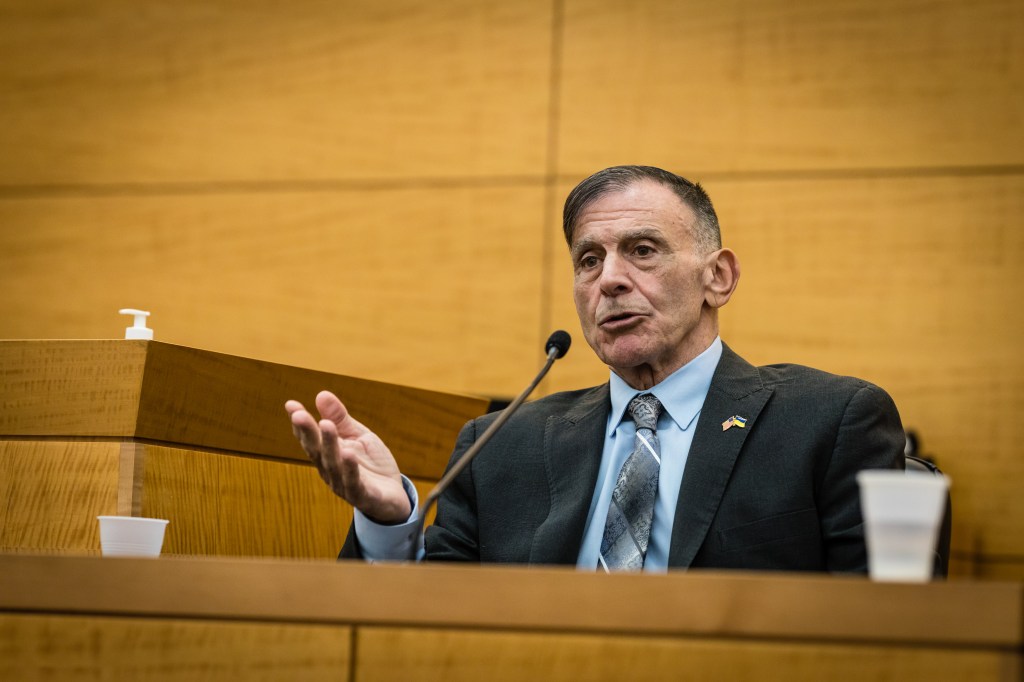 Detective Louis Scarcella speaking into a microphone on the witness stand during a court hearing at New York State Supreme Courthouse