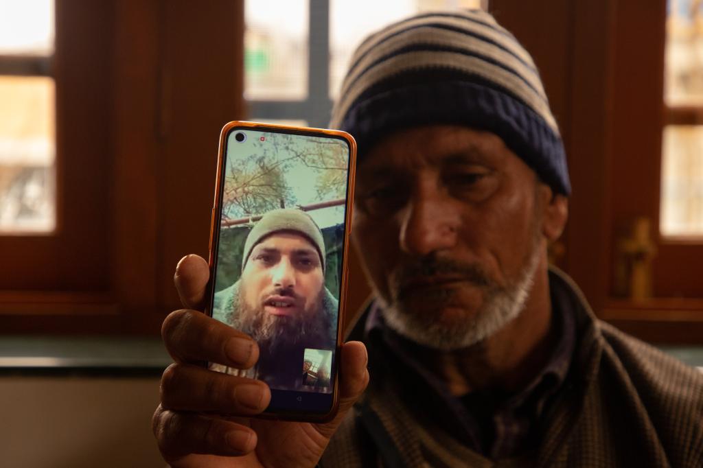 A father of Azad Yousuf Kumar, holds a smart phone displaying the photos of Azad Yousuf Kumar, wearing military uniform, at Pulwama village