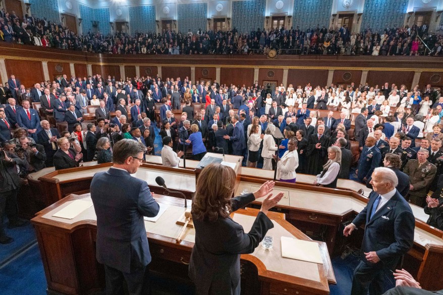 President Joe Biden arrives to deliver the State of the Union address to a joint session of Congress with a group of people applauding.