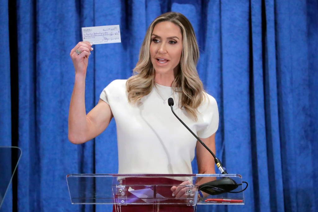 Lara Trump, the newly elected co-chair of the Republican National Committee, holds up a donation check as she gives an address during the general session of the RNC Spring Meeting Friday, March 8, 2024, in Houston. 