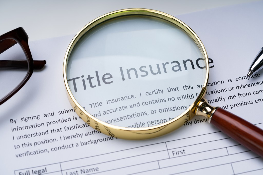 A title insurance form on a table with a magnifying glass over it.