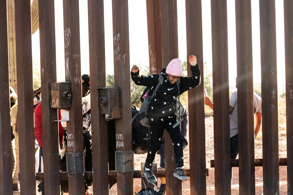 A migrant child jumps to cross the border wall through a gap into the U.S. from Mexico, as the number of migrants surges in the border town of Lukeville, Arizona, U.S. December 12, 2023.