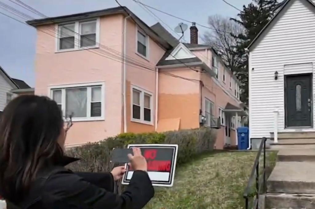 Woman takes photo of "No Trespassing" sign in front of house.