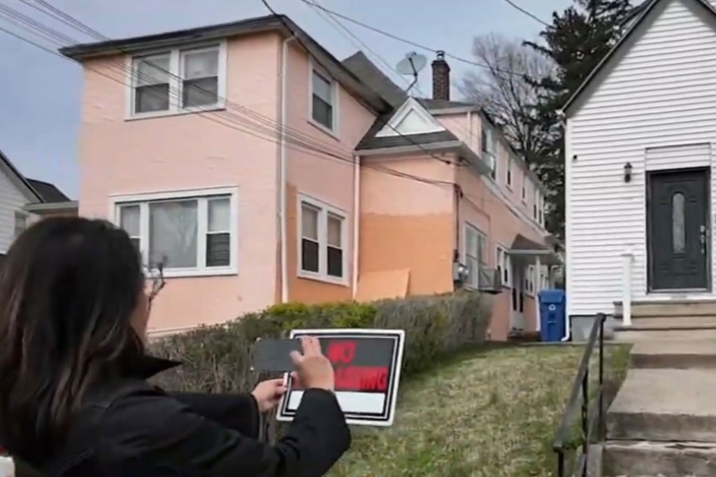 Woman takes photo of "No Trespassing" sign in front of house.