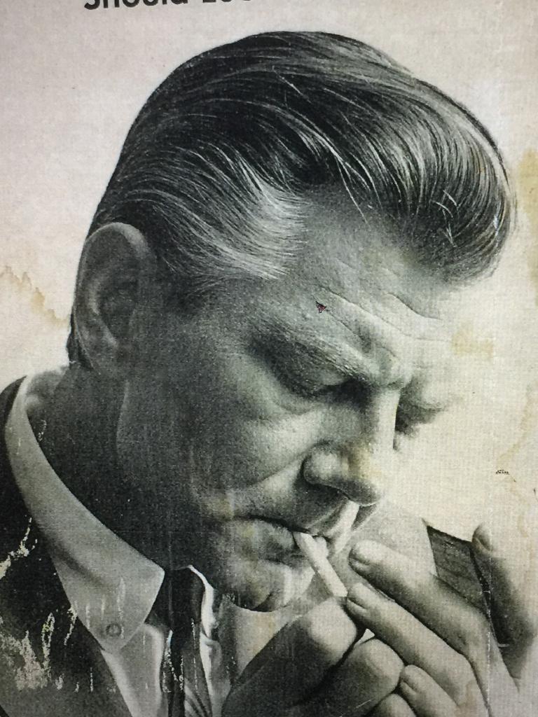 Bill Jorgensen seen in old clipping lighting a cigarette, wearing a suit and hair coiffed back.