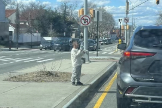 Migrant kid on a median of a busy street, selling bottled water on a cold day without a jacket