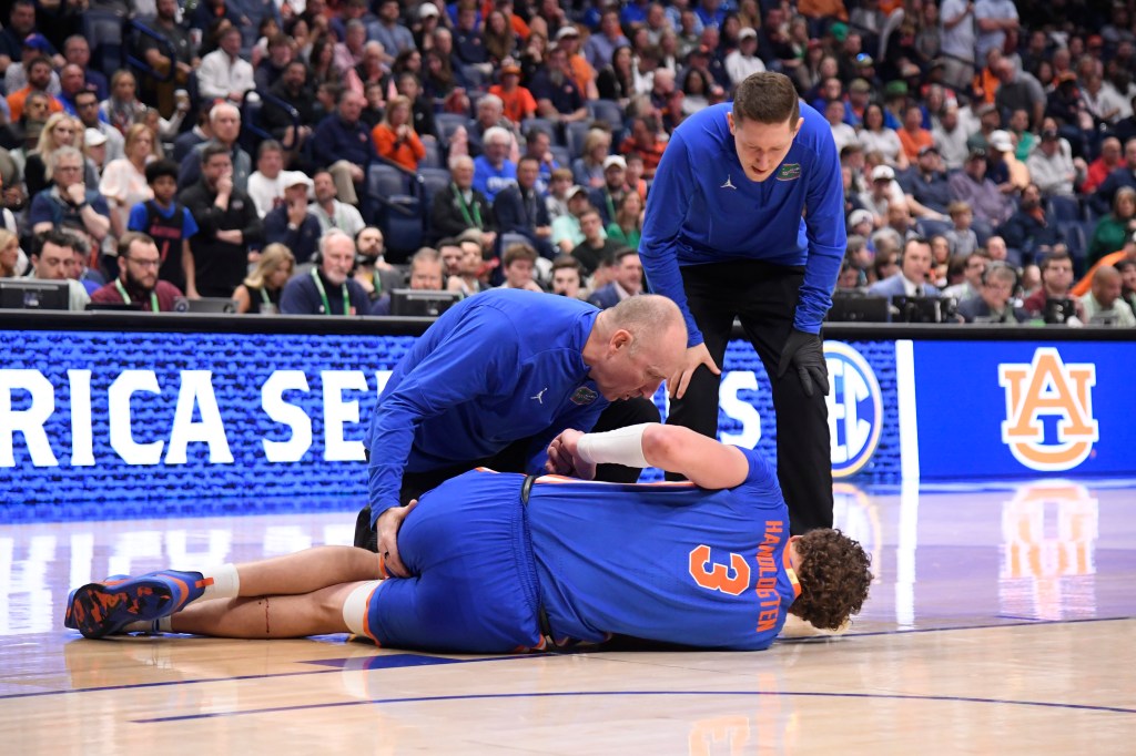 Trainers tend to Florida's Micah Handlogten after he suffered a gruesome leg injury during Sunday's SEC championship game.