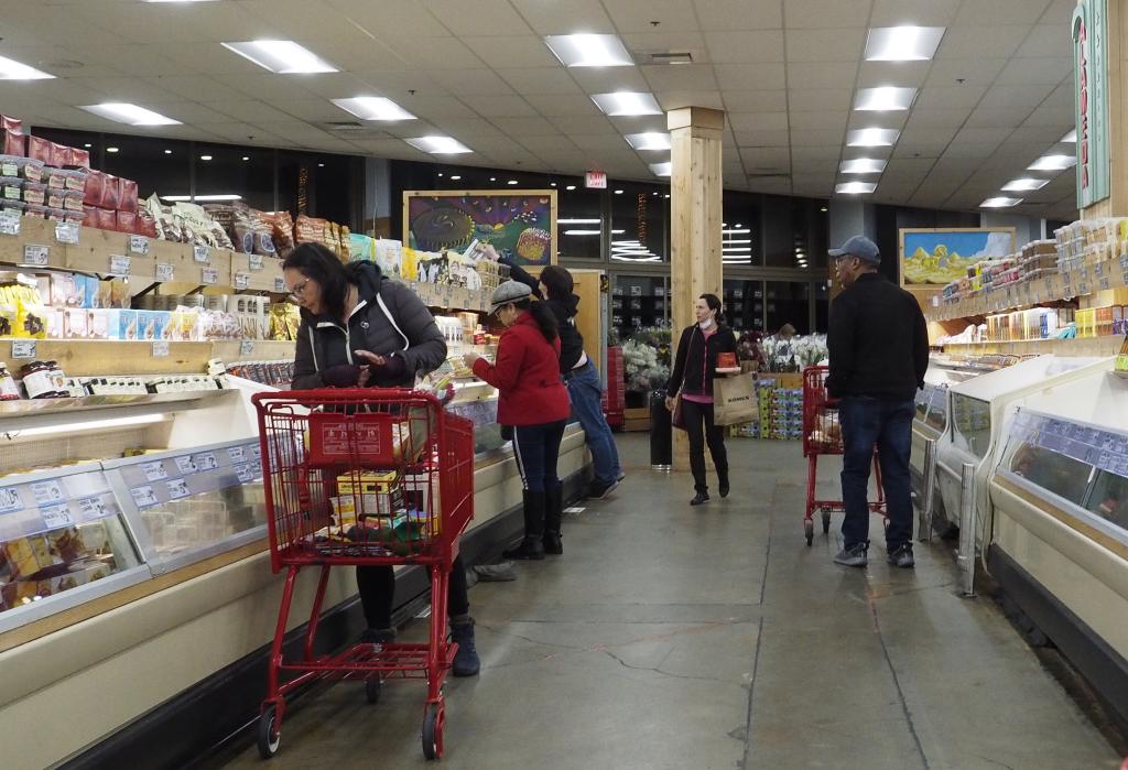 Customers shopping in the frozen, prepared food aisle in a grocery store in Alameda, California, USA