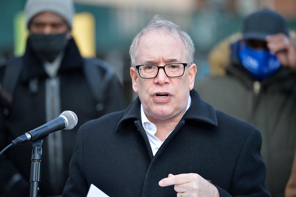 Scott Stringer speaking at a microphone, outside wearing a black coat