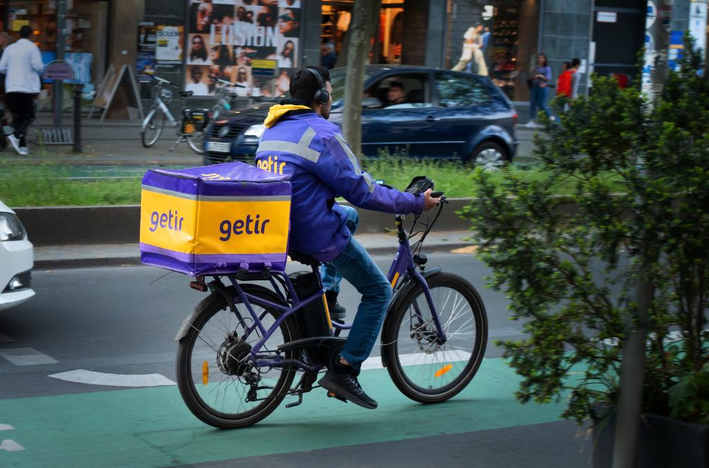 A messenger from Getir delivery service riding an e-bike along a green bike path in the Steglitz district of Berlin.