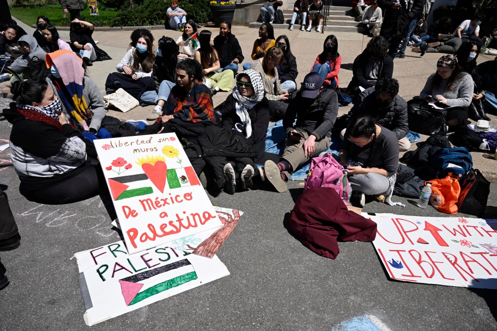 300 pro-Palestinian protesters sitting on the ground with homemade signs reading 'Free Palestine' and 'Up with Liberation' at Yale University intersection