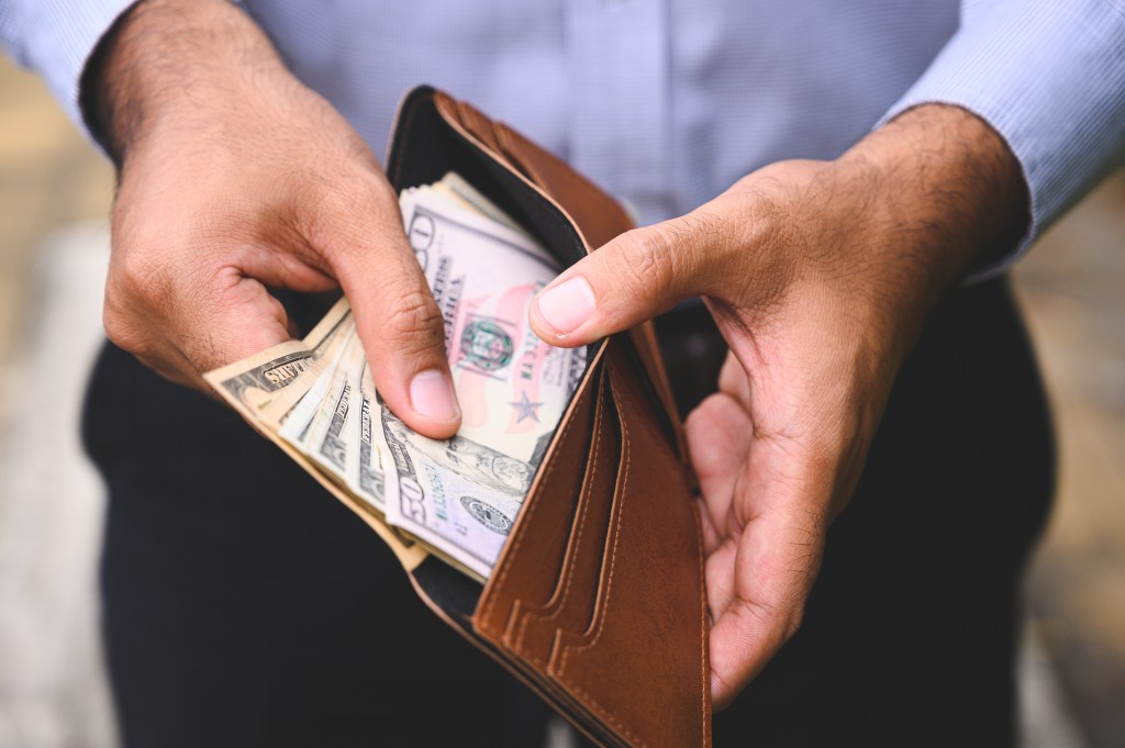 Close-up of a business man counting a spread of cash in his wallet