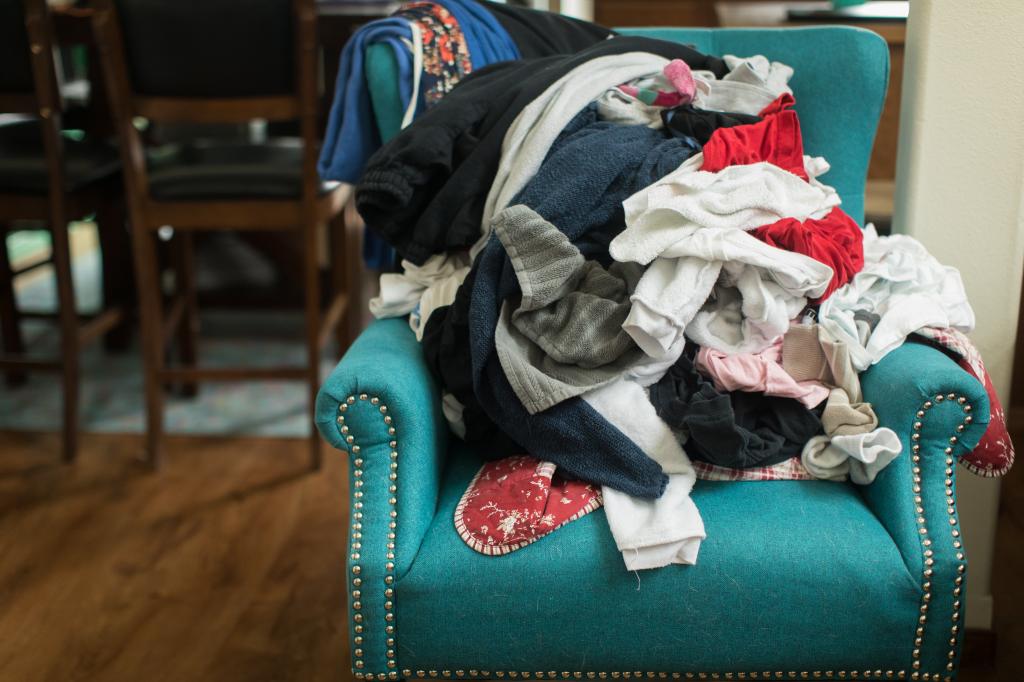 Pile of various clothes on a colorful chair in a home setting