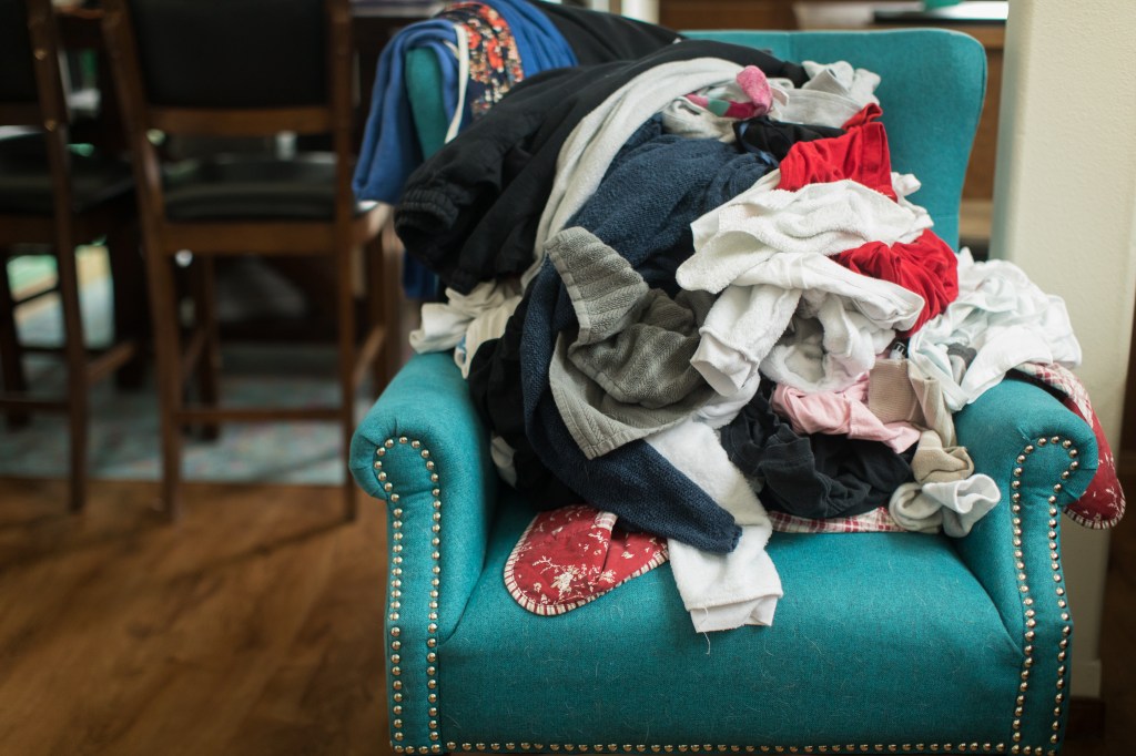 Pile of various clothes on a colorful chair in a home setting