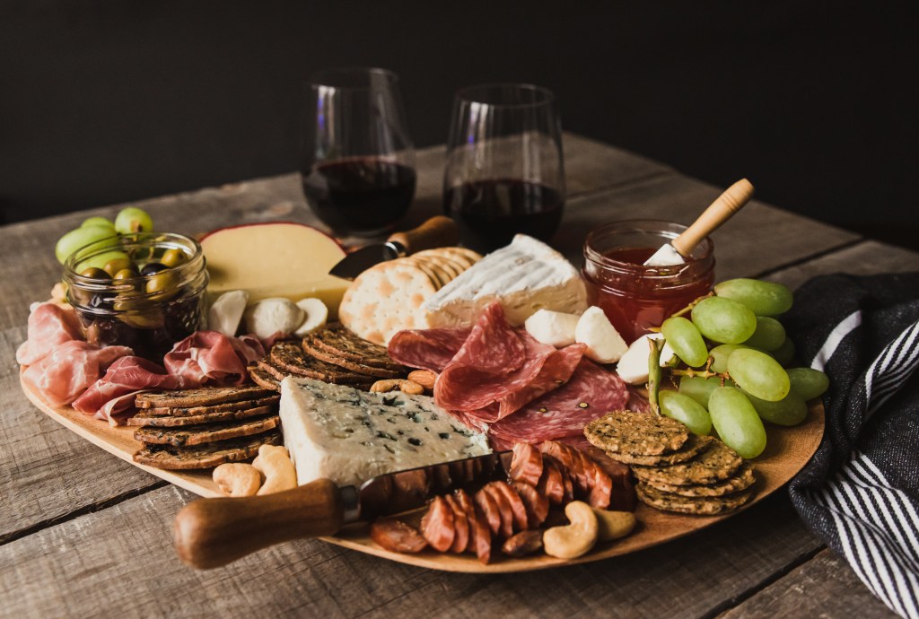 Close up of charcuterie board and glasses of wine on wooden tabl