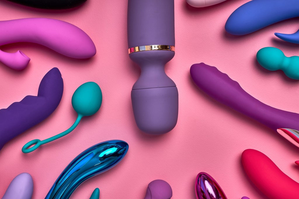 purple big phallus among small sex toys isolated on pink background