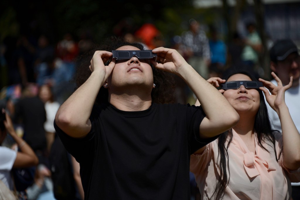 A couple is seen observing the annular solar eclipse with special filter glasses for the sun at the National Autonomous University of Mexico.