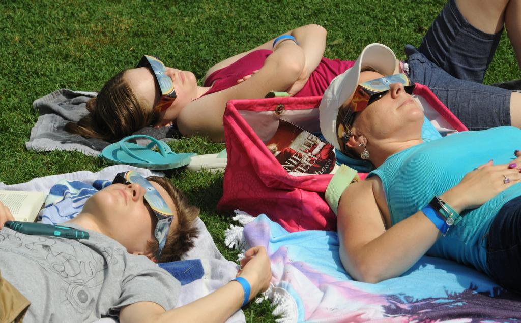 A mother watches the solar eclipse where her two teenage children in 2017 in Massachusetts. 