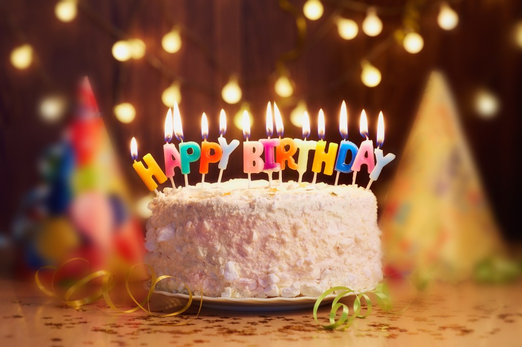 Birthday cake with candles, bright lights bokeh.