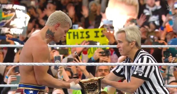 Referee Charles Robinson hands the WWE Universal championship to Cody Rhodes.