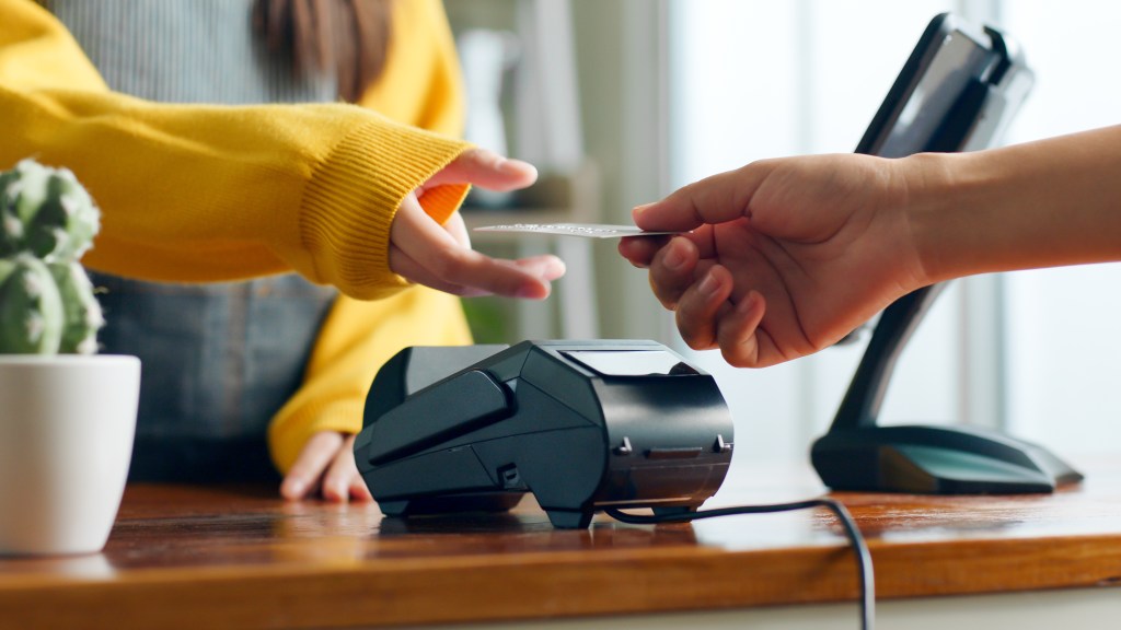 A customer handing over a credit card for payment at a cafe restaurant, showcasing cashless technology concept