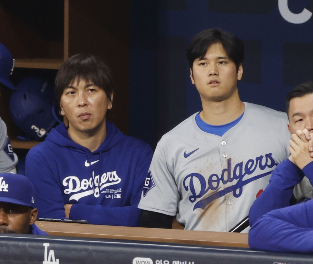 Shohei Ohtani (R) of the Los Angeles Dodgers and his interpreter Ippei Mizuhara watch the MLB season-opening game against the San Diego Padres from the dugout at Seoul's Gocheok Sky Dome on March 20, 2024.  