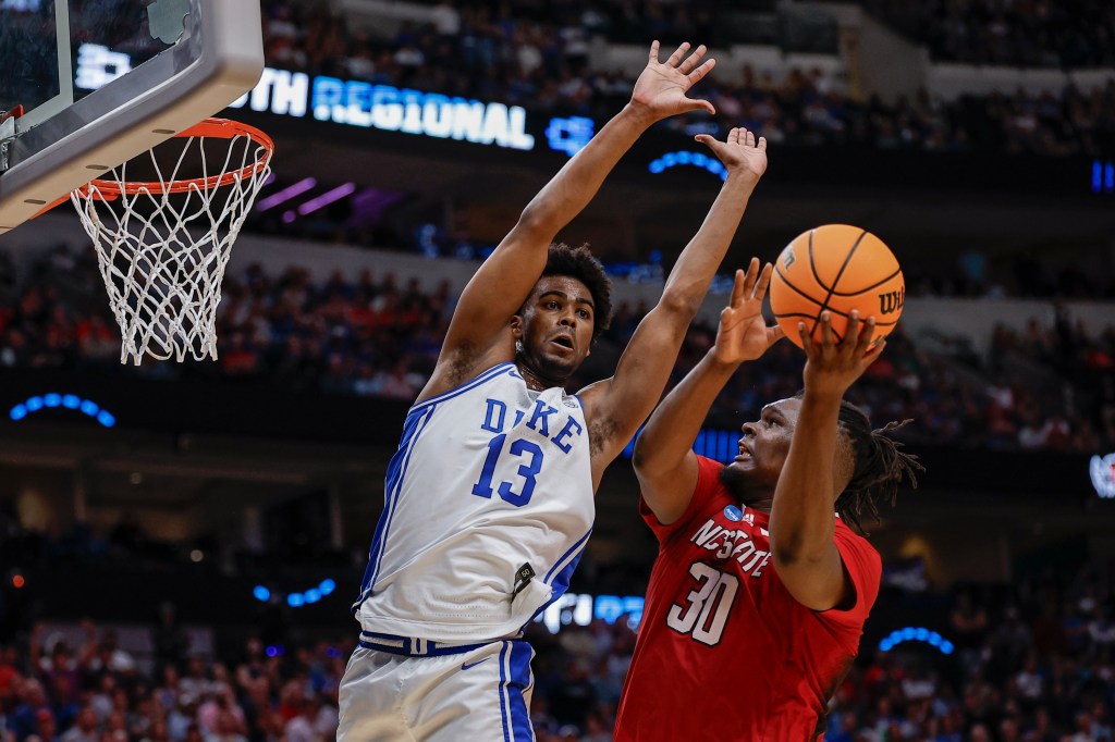 Carolina State's DJ Burns Jr., right, shoots against Duke's Sean Stewart during the second half of an Elite Eight college basketball game.