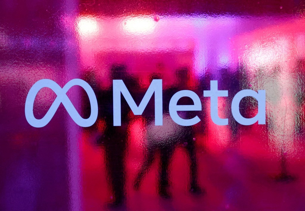 People walking behind a Meta Platforms logo at a conference in Mumbai, India in September 2023