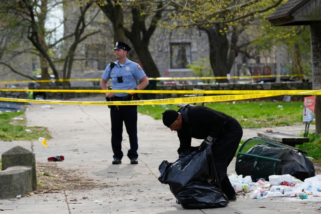 A person picks up debris in the aftermath of a shooting at an Eid event in Philadelphia, Wednesday, April 10, 2024. 