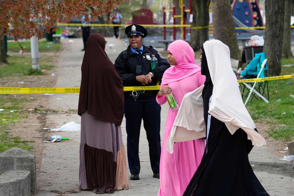 A person talks to an officer in the aftermath of a shooting at the Eid al-Fitr event.