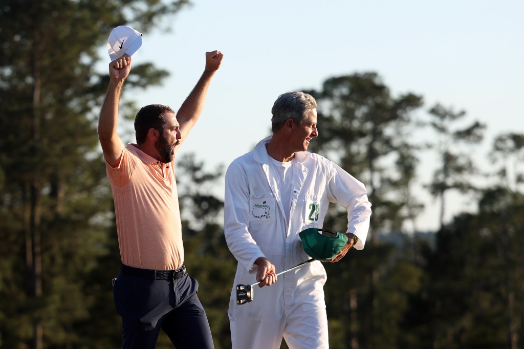 Scottie Scheffler (l) and caddie Ted Scott celebrate on the 18th green after winning the 2024 Masters Tournament at Augusta National Golf Club on April 14, 2024.