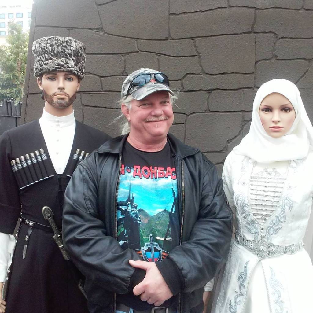 Russell Bentley poses with two mannequins dressed in traditional Russian clothing.