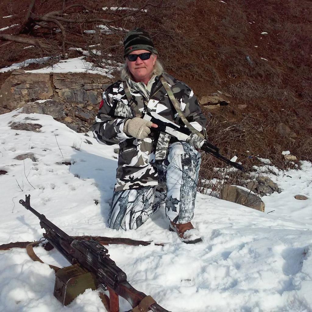 American Russell Bentley posing in Ukraine, where he knelt in the snow with a long gun in his hands while wearing camoflauge clothing.