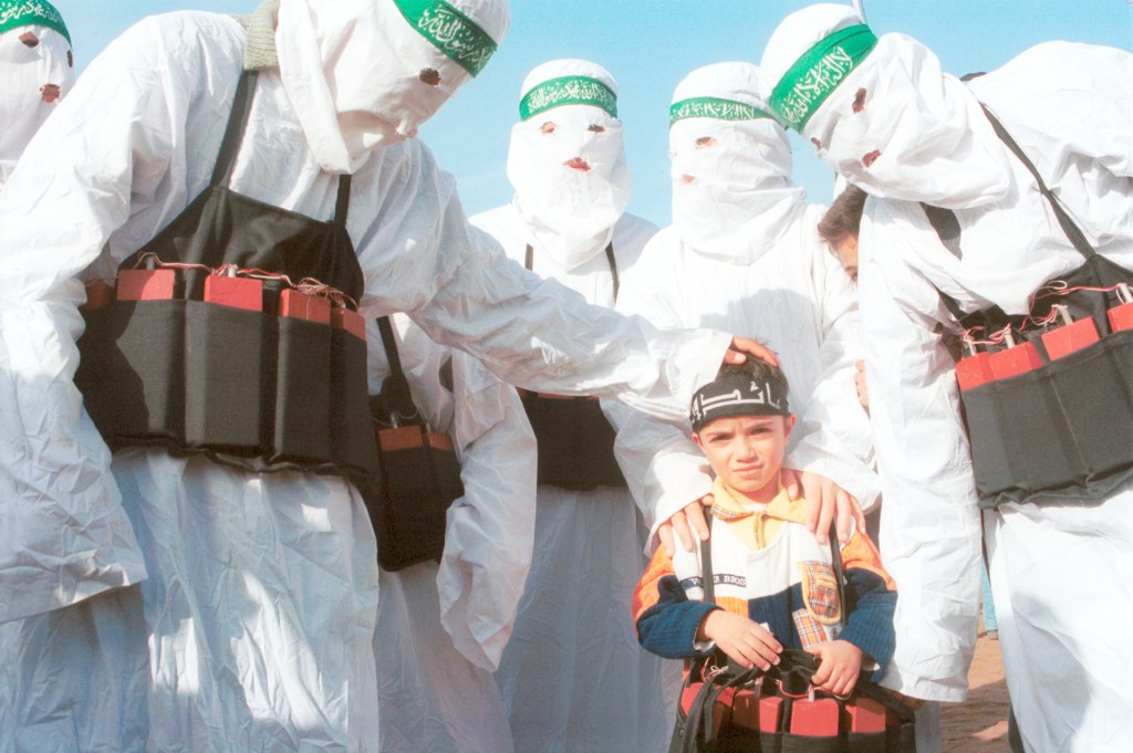 Palestinians dressed as suicide bombers with a child carrying fake explosives during a Hamas march in Lebanon on Dec. 9, 2001.