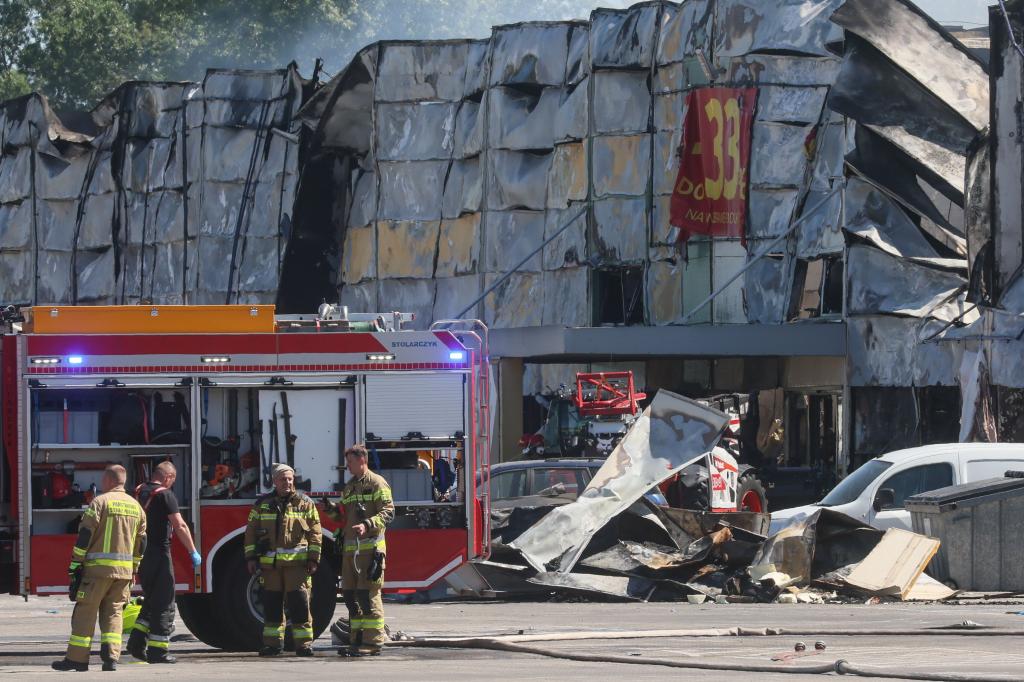 Firefighters stand next to a shopping complex during a fire in Warsaw, Poland