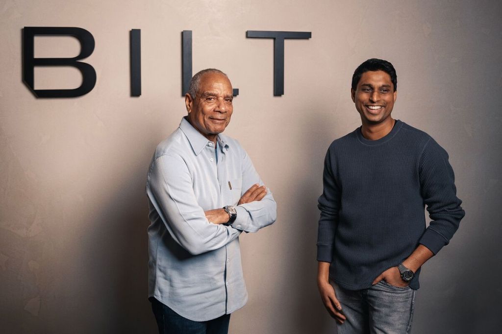 Ken Chenault and Ankur Jain standing in front of a wall with letters on it